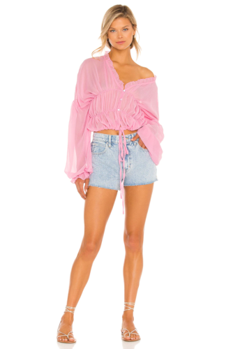 Pink sheer ruffled blouse paired with denim shorts and sandals