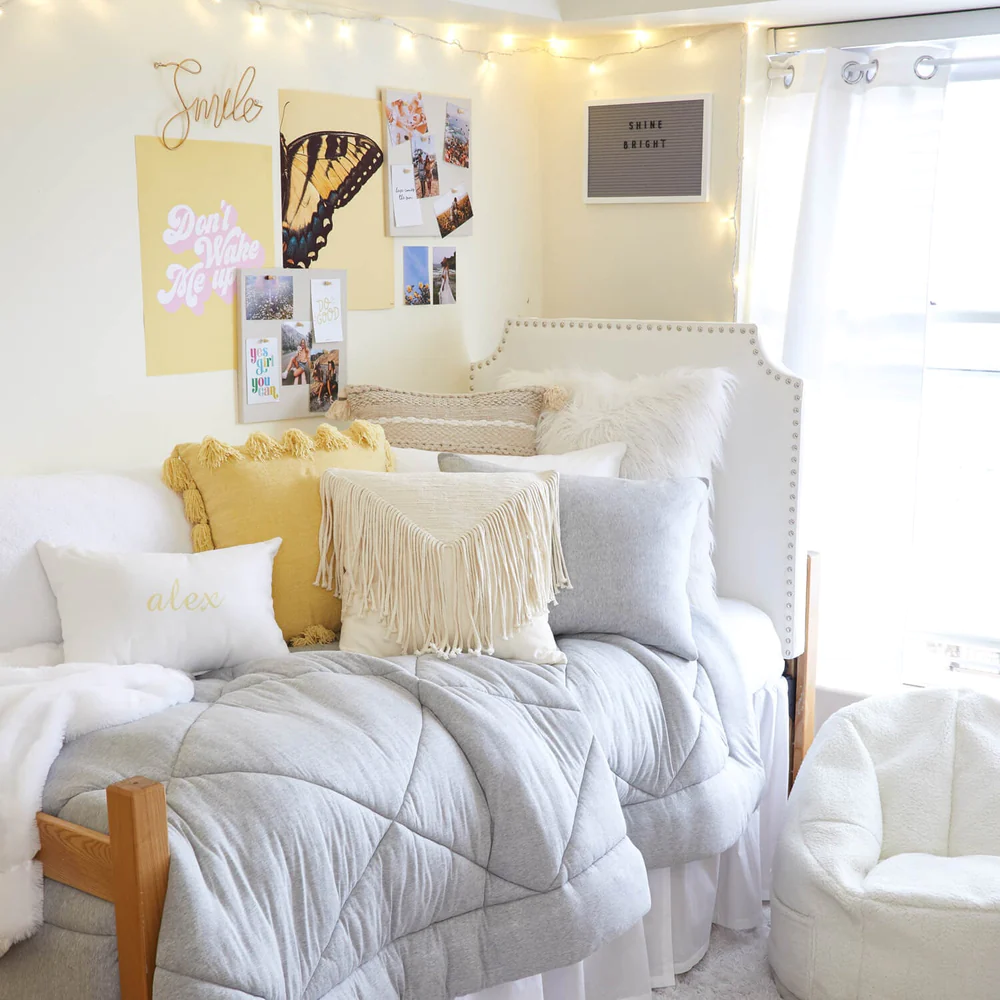 A bunch of pillows layered on a bed in a dorm room