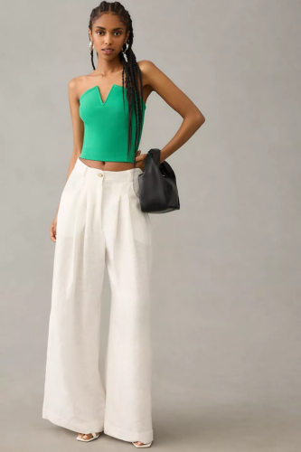 Brightly colored corset outfit with bright green corset top, white wide leg pants, and white heels paired with a black mini purse