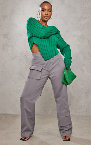 Plus size outfit idea for Mardi Gras with gray cargo pants, heels, and a green cropped knit top and mini bag