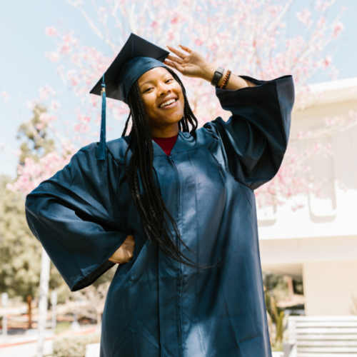 Black woman rocking long braids and wearing graduation cap as she graduates